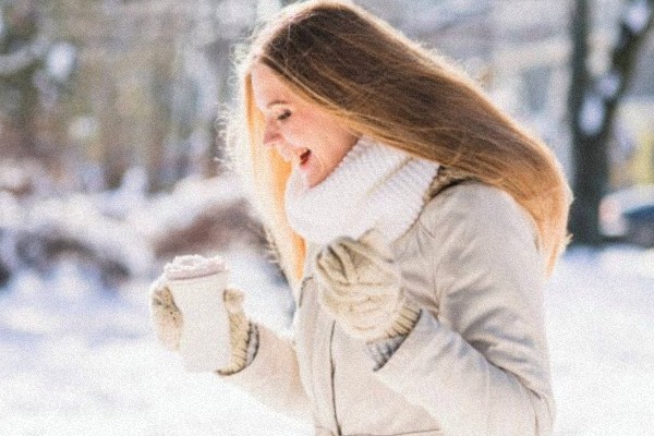 usmievajúca žena v zime počas pekného počasia, ktorá drží termosku